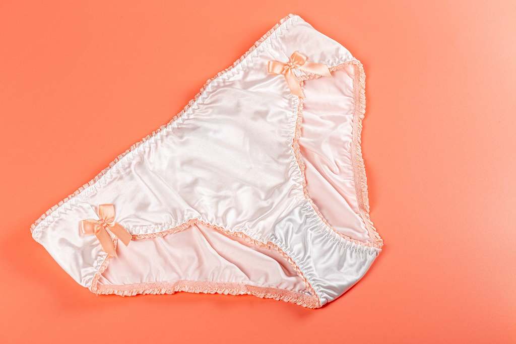 Silk white womens panties on a peach background