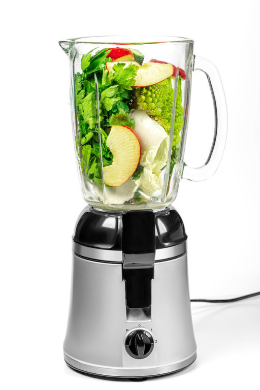 Blender with cabbage, apple slices, cucumber and parsley on a white background
