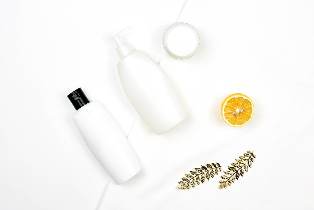 White bottles of lemon-based beauty products on white background
