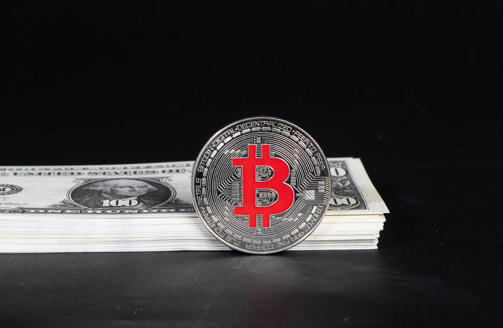 Silver Bitcoin with stack of money