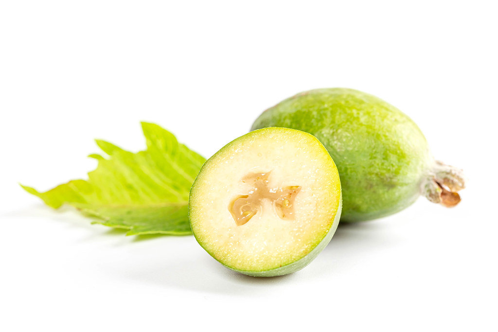 Whole and half feijoa fruit with green leaf