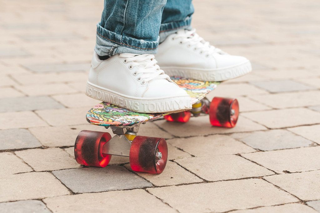 Girl in white sneakers on a skateboard outdoors