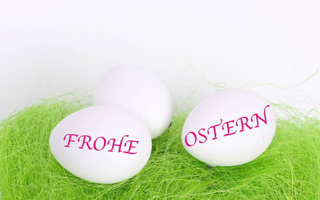 Easter eggs on green grass with Frohe Ostern text