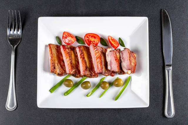 Appetizing smoked ribs with tomatoes, jalapenos and olives, top view