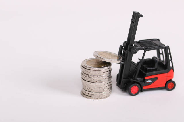 Toy forklift lifting coins, business concept