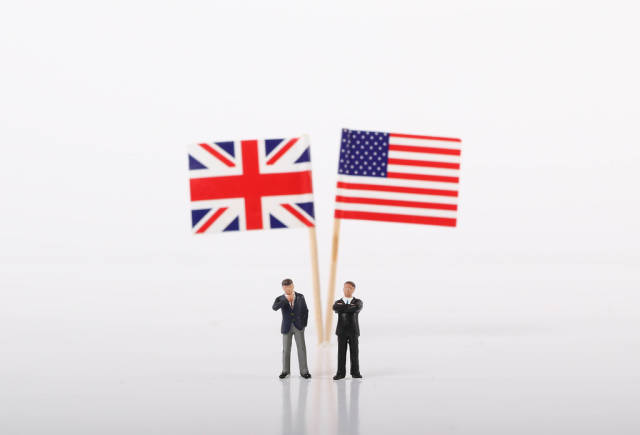 Two businessman standing in front of flags of United Kingdoma and USA