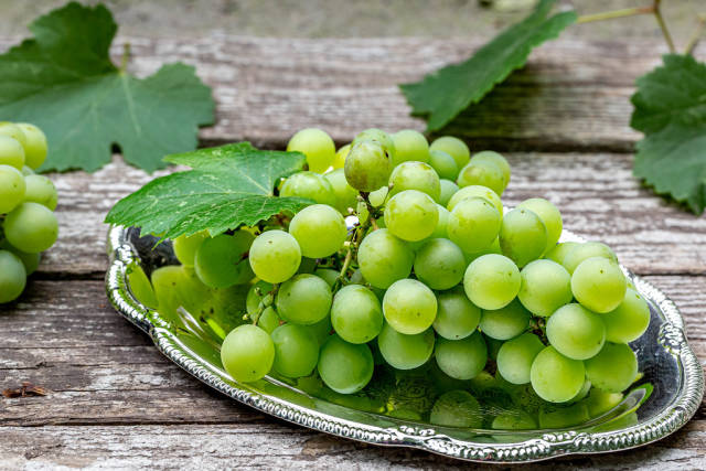Green bunch of grape on gray wooden background