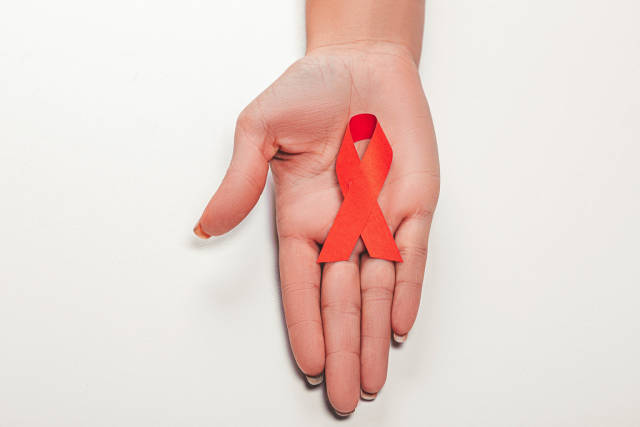 Aids red ribbon on womans hand support for World aids day and national HIV/AIDS and aging awareness month concept