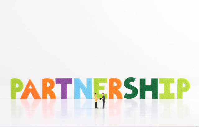 The word Partnership with two businessman shaking hands on white background