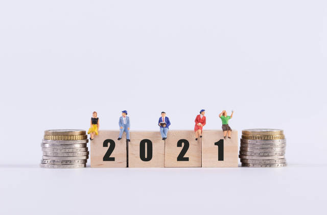 Stack of coins and group of people sitting on wooden cubes with 2021 text