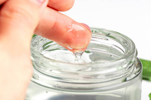 Close-up of a womans hand and aloe Vera gel in a glass jar