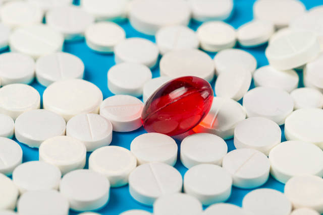 One red capsule with many white tablets