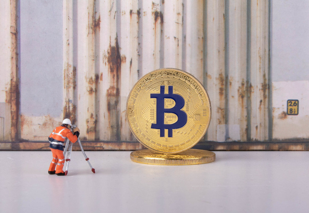 Worker taking photo of a golden Bitcoin