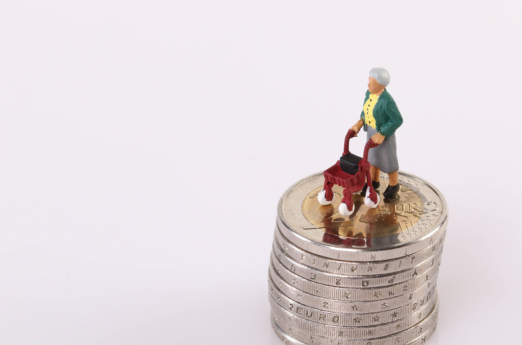 Old women standing on top of stack of coins on white background