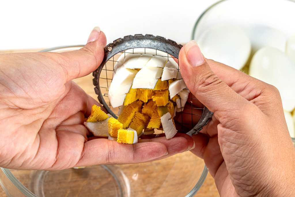 Hard-boiled egg cut on egg slicer in female hands