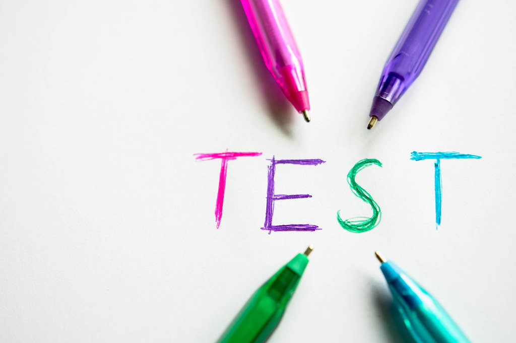 Kugelschreiber verschiedener Farben zeigen auf das Wort TEST