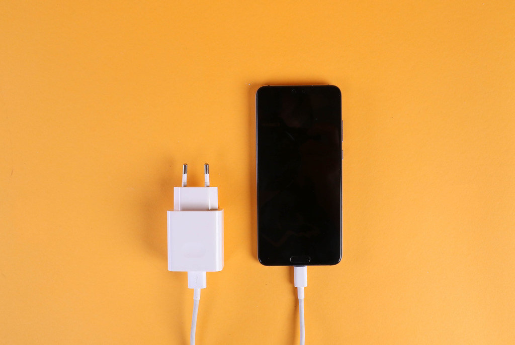 Mobile phone and charger cable on orange background