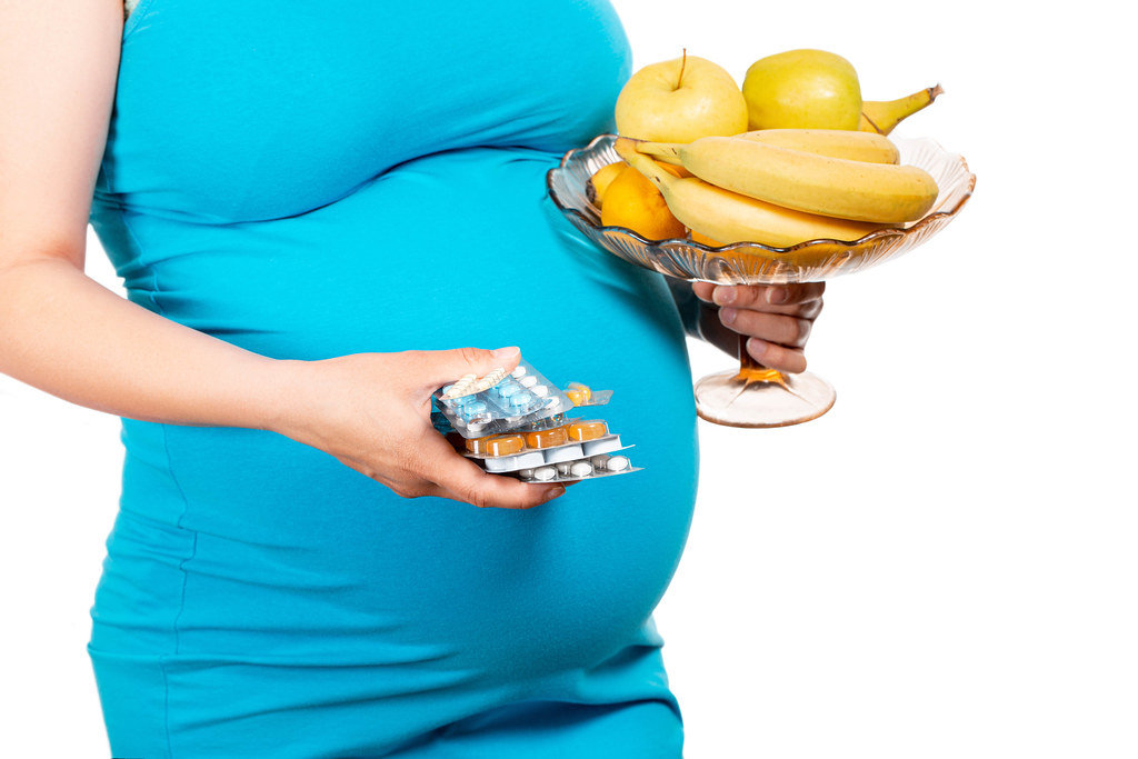 Young womans holding blister packs of pills and fresh fruits. Concept receiving vitamins in pregnancy time