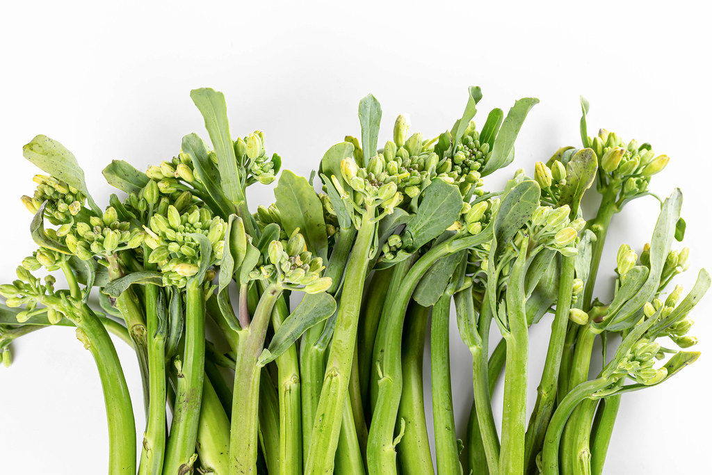 Fresh raw broccolini twigs on white, top view