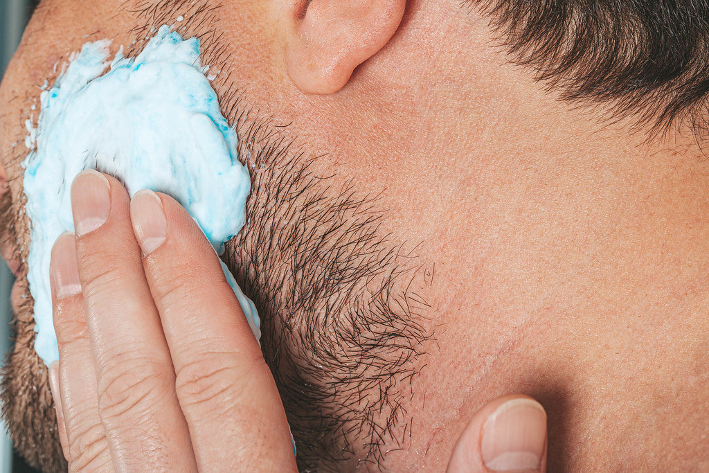 Portrait of male putting shaving foam on his beard. Skin care concept