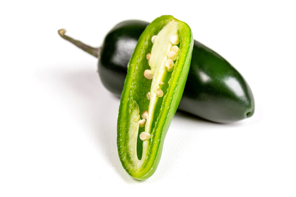 Jalapeno pepper whole and half on a white background