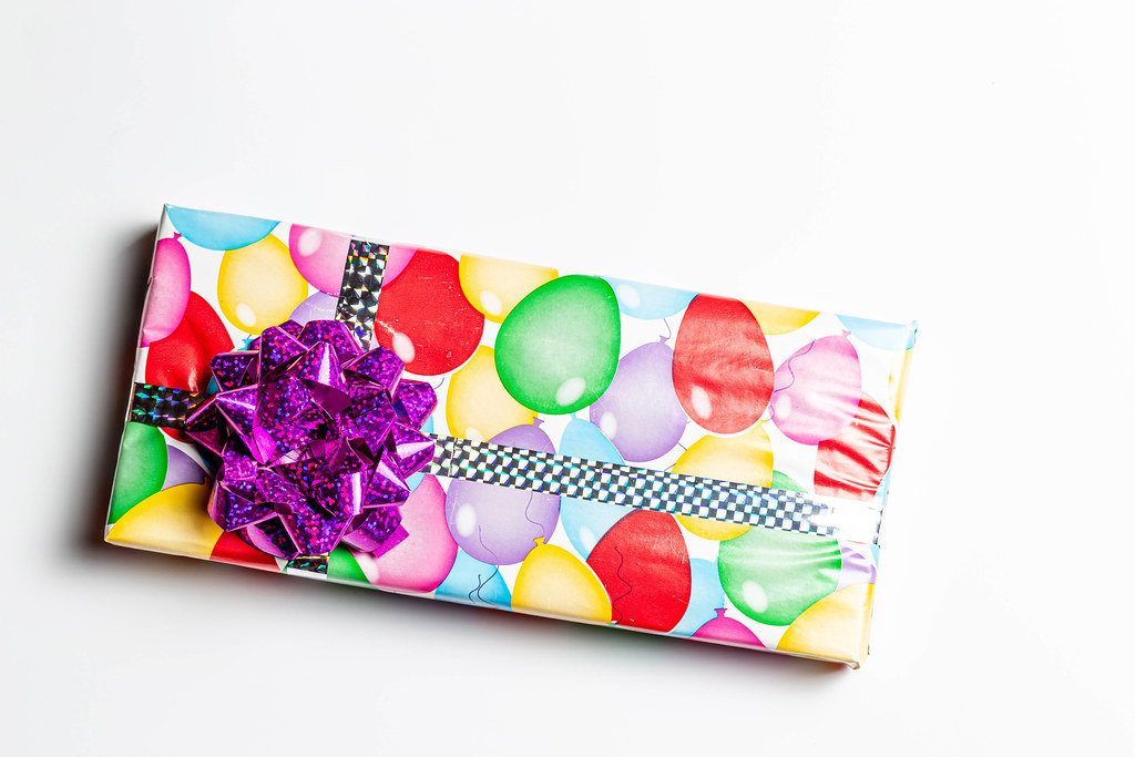 Gift with a bow in multicolored paper on a white background