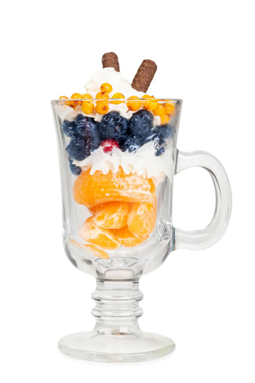 Glass mug with fruit dessert on white background