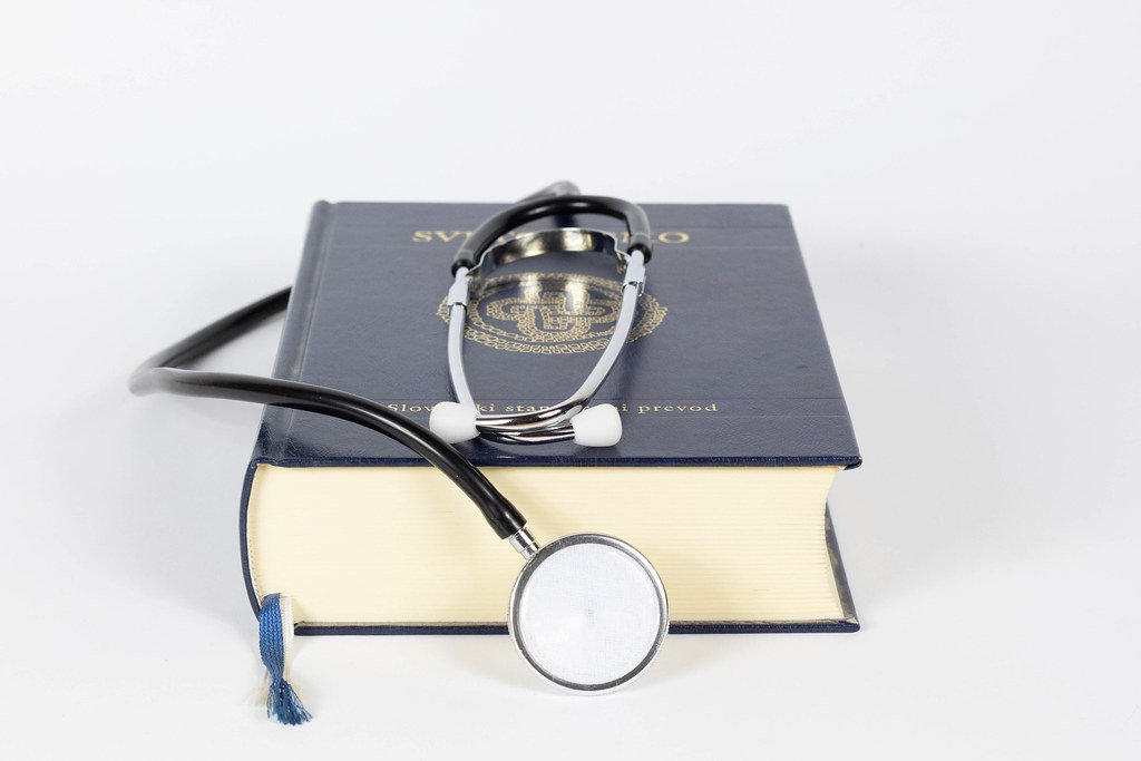 Buch und Stethoskop vor weißem Hintergrund