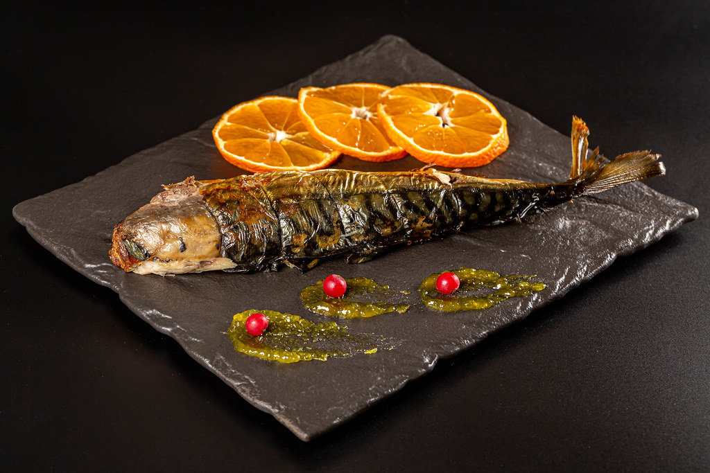 Baked mackerel on a dark background with orange