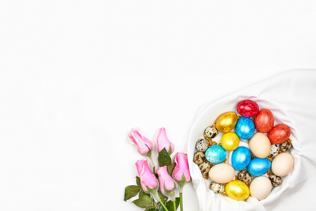 Weißer Ostern Hintergrund mit Platz für Text: bunte Eier, Wachteleier und Rosen