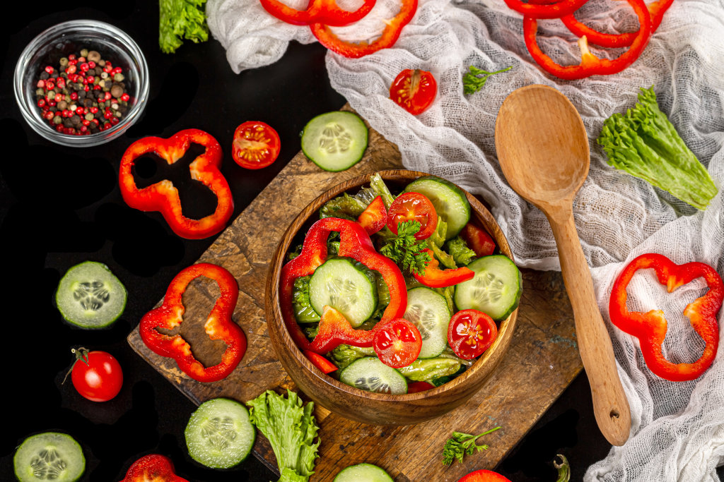 Salad with cucumbers and bell peppers in a wooden bowl, top view