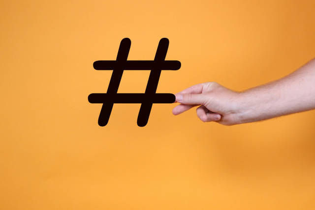 Hand holding big hashtag on orange background
