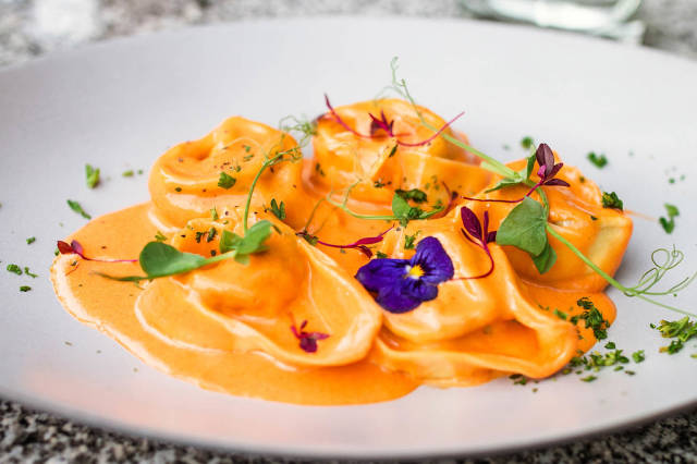 Tortellini with sauce and flowers. Close up