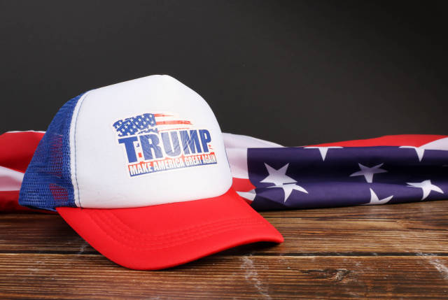 American flag on wooden table with Trump trucker hat