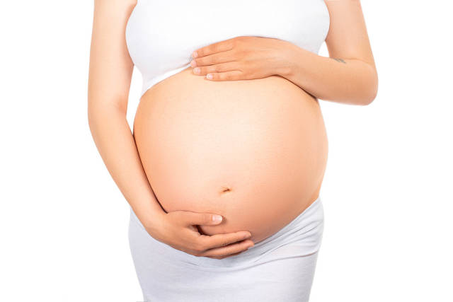 Young pregnant woman waiting for her babys birth holding her tummy on white background