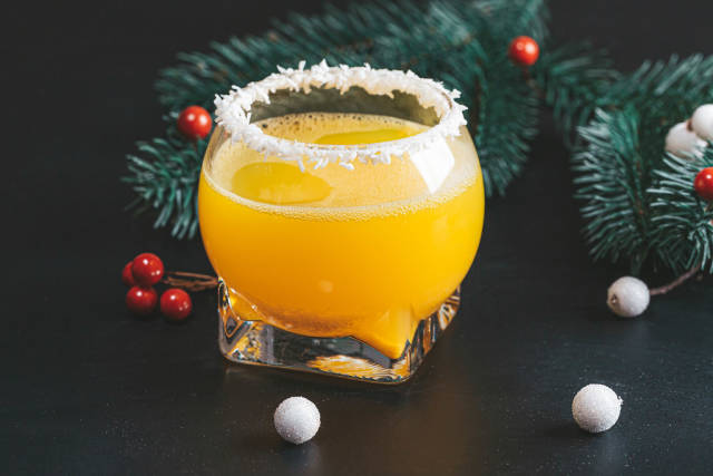 Orange cocktail on a new year background with Christmas tree branches