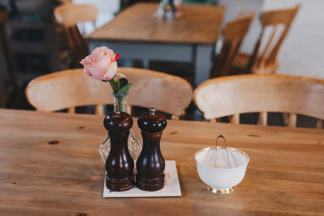 Tischutensilien in einem Restaurant. Rose in einer Vase, Zuckerdose, Salzmühle und Pfeffermühle