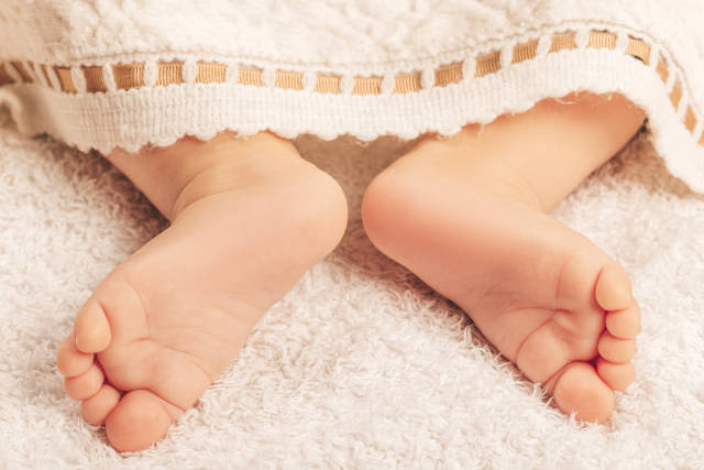 Cute feet of sleeping newborn baby in light bedroom. Family, motherhood, love, health and care