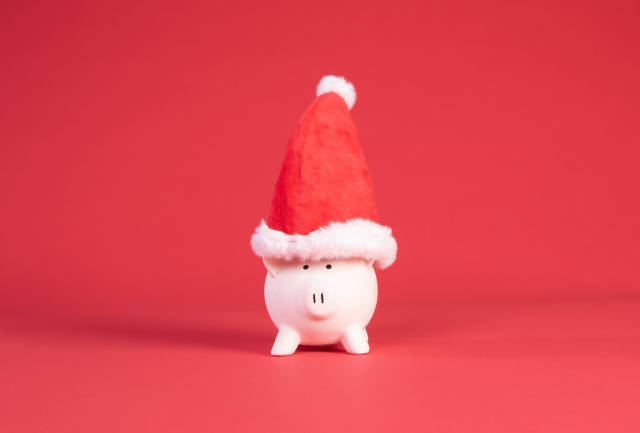 Piggy bank with Christmas hat on red background