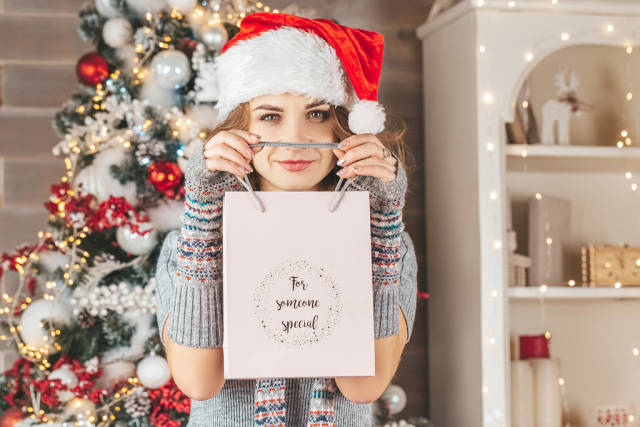 Gift bag in the hands of a woman in a santa hat