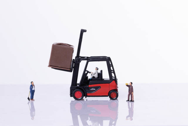Red forklift with miniature workers on white background