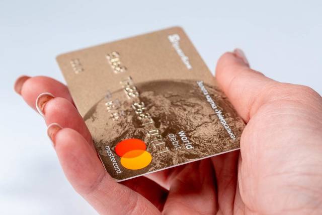 Mastercard - Kreditkarte in einer Frauenhand, vor weißem Hintergrund