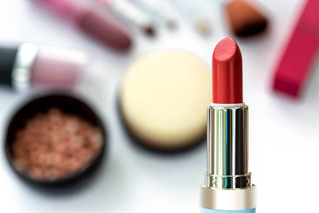 Red lipstick on blurry cosmetics background