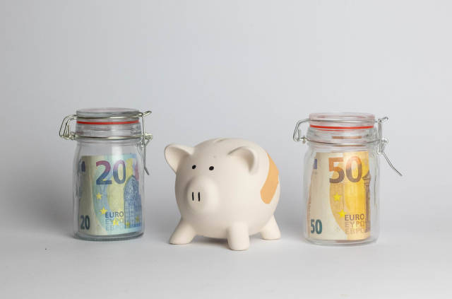Geldsparen - Ein Sparschwein aus Porzellan und Einmachgläser mit Geldscheinen