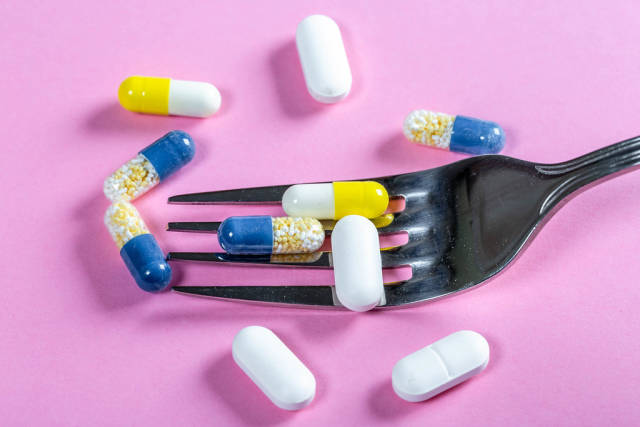 The concept of drug nutrition-encapsulated medicines with a fork on a pink background (Flip 2019) (Flip 2019) Flip 2019