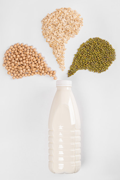Milk bottle with oatmeal, chickpeas and mung beans on white back