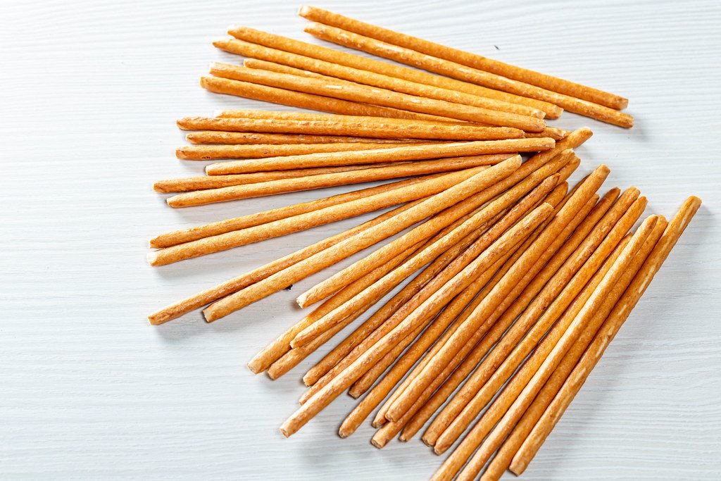 Süße Cracker-Stäbchen ähnlich zu den zum Aperitif gereichten Grissinis auf weißem Tisch