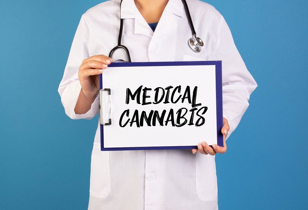 Arzt hält einen Schild mit der Schrift Medical cannabis im blauen Hintergrund