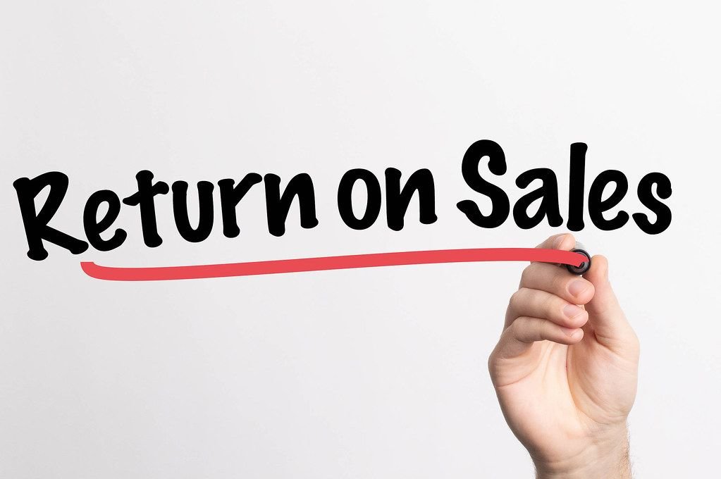 Hand schreibt das Wort "Umsatzrendite" auf ein Whiteboard