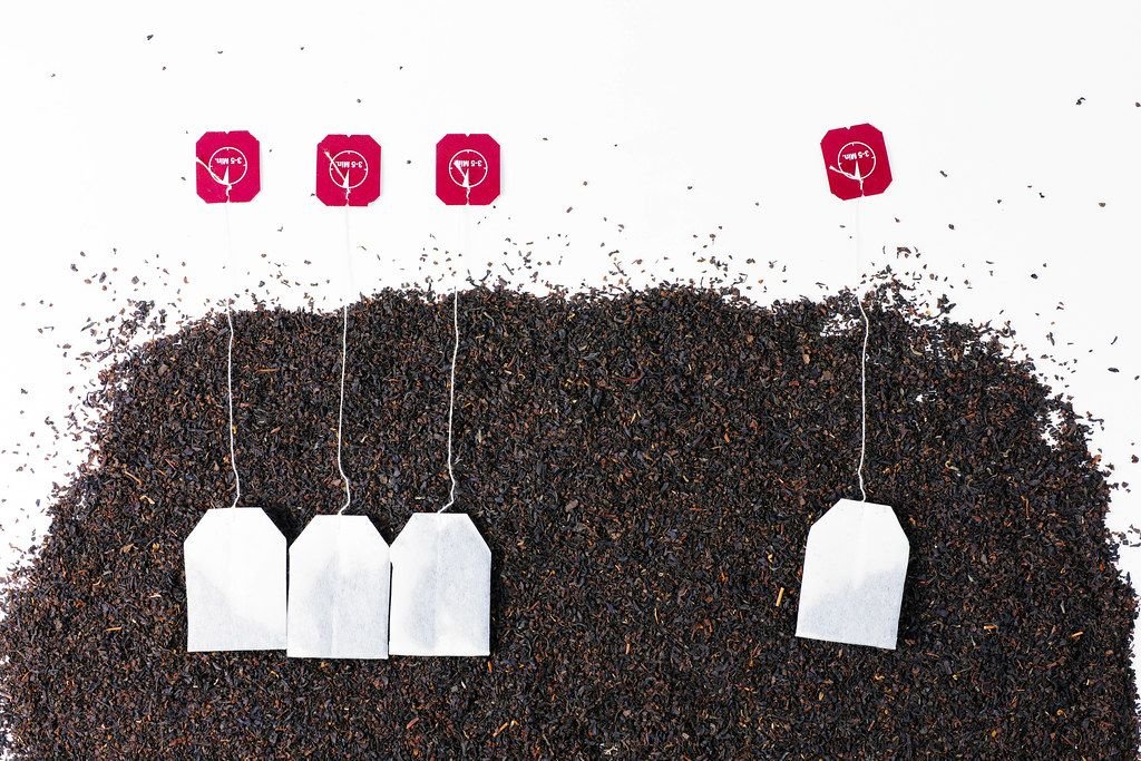 Getrockneter Tee und neue Teebeutel auf weißem Hintergrund